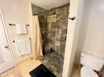 Spacious walk-in marble shower with detachable shower head and a fixed shower head.
